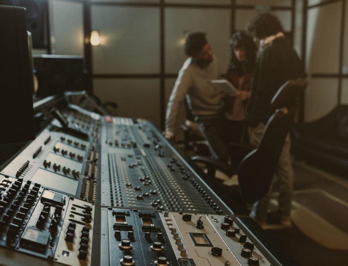blurred group of musicians spending time at recording studio with graphic equalizer